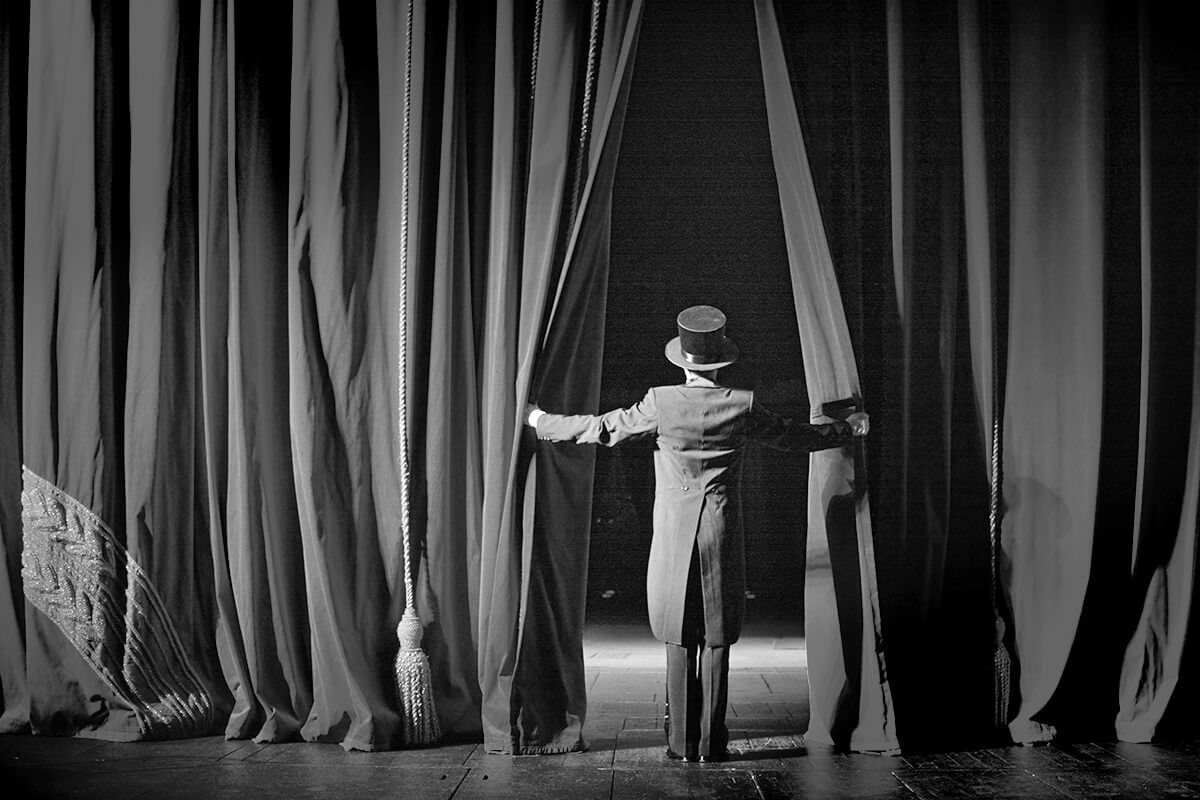 Actor in a tuxedo theatre closes the curtain.