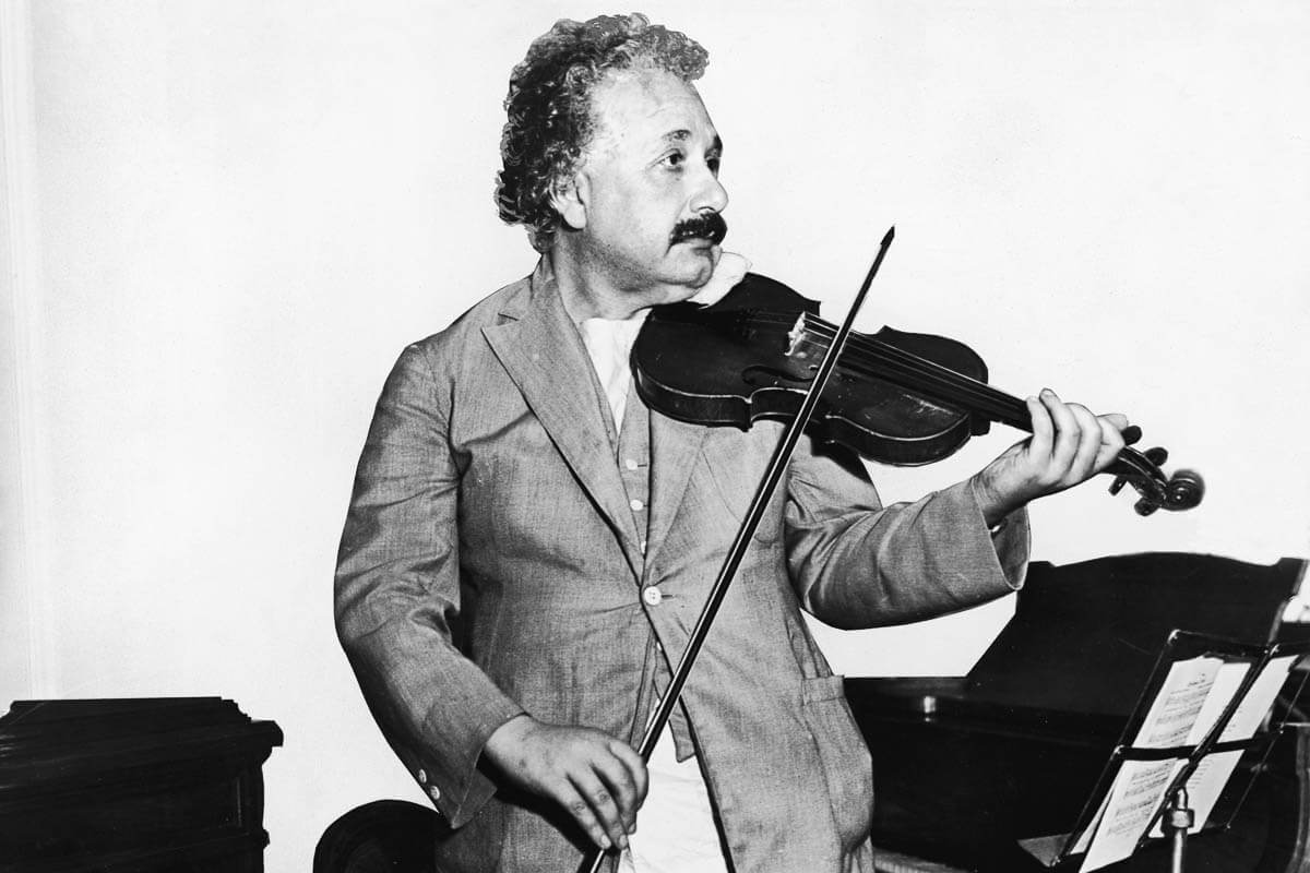 Mathematical physicist Albert Einstein plays a violin in a music room.