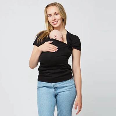 A woman wearing jeans and a black top with a baby sitting inside a built-in pouch