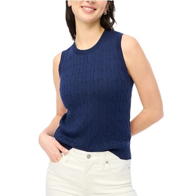A woman wearing a navy sweater shell and white pants